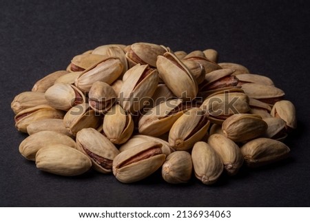 Heap or pile of pistachios nuts in the peel, isolated still life on black background. Pistachios closeup for design and print. Nuts collection