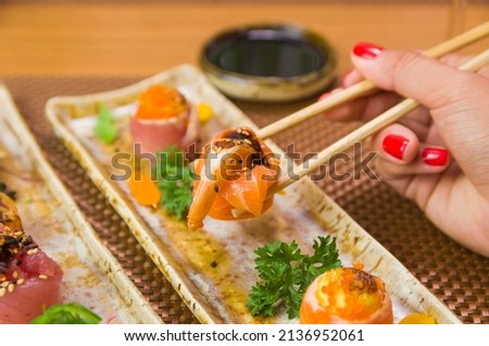 Woman eating delicious gunkan sushi, closeup on chopsticks