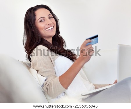 Shopping is just a click away. Portrait of an attractive woman holding a credit card while using a laptop.