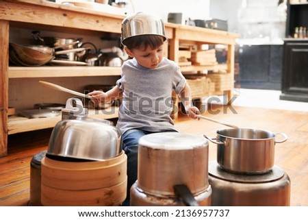 Rock star in the making. A young boy playing drums on pots and pans. Royalty-Free Stock Photo #2136957737