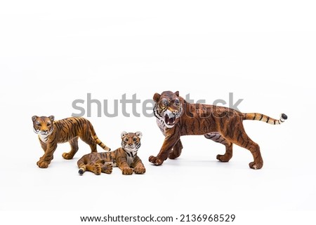 Toy animal figures tiger and tiger cubs on white.