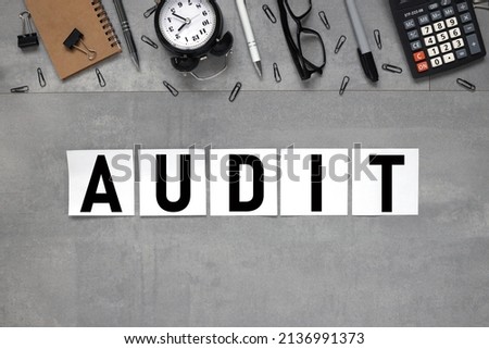 AUDIT. text on white stickers on a gray background near stationery