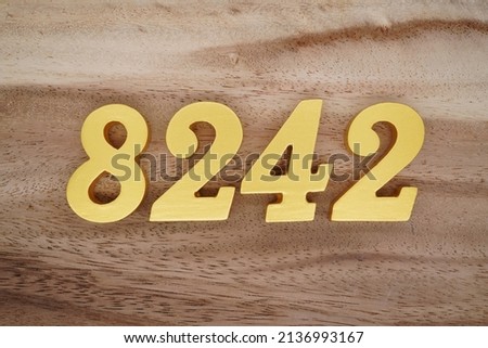 Wooden  numerals 8242 painted in gold on a dark brown and white patterned plank background.