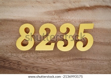 Wooden  numerals 8235 painted in gold on a dark brown and white patterned plank background.