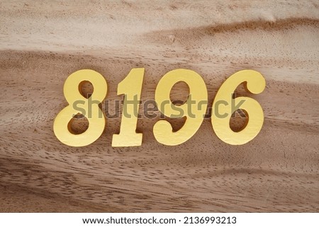 Wooden  numerals 8196 painted in gold on a dark brown and white patterned plank background.