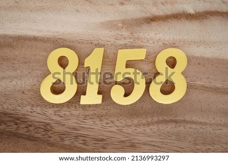 Wooden  numerals 8158 painted in gold on a dark brown and white patterned plank background.