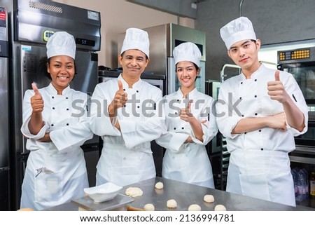 Asian Chefs  baker in a chef dress and hat, cooking together in kitchen.Team of professional cooks in uniform preparing meals for a restaurant in the kitchen. Royalty-Free Stock Photo #2136994781