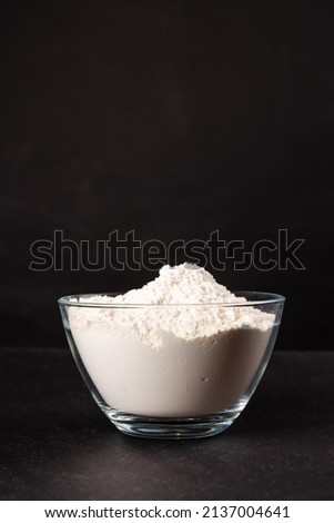 flour in a glass bowl on black background