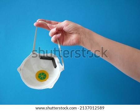 
hand takes medical respiratop on blue background, coronavirus medical mask. protective mask from covid-19, closeup Royalty-Free Stock Photo #2137012589
