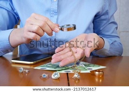 Pawnshop worker verify jewellery and photo or video camera and give money. Customers Buy and Sell Precious Metals, Jewels, Ancient Coins and Second Hand Electric Appliances. Closeup Royalty-Free Stock Photo #2137012617