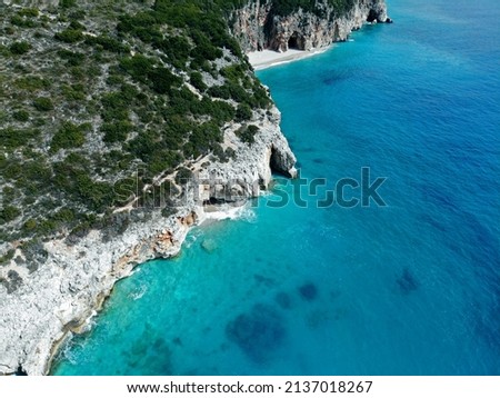 Drone aerial picture view of Gipje beach wit rocky cliffs and grey stones. Small waves and turquoise water and corals. Green bushes on top of grey hills. Hidden beaches and secret lagoons.