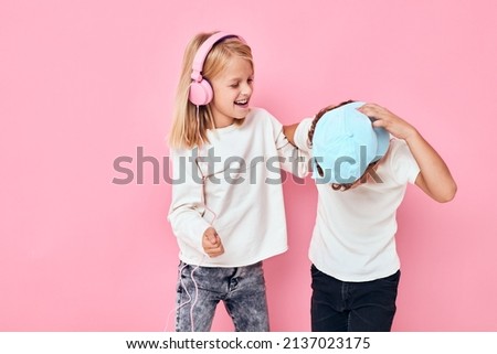 Stylish little boy and cute girl listening to music pink color background