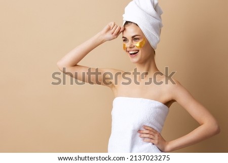 young woman with a towel on his head gesturing with his hands skin care beige background