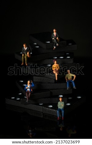 miniature people on dominoes vertical Black background