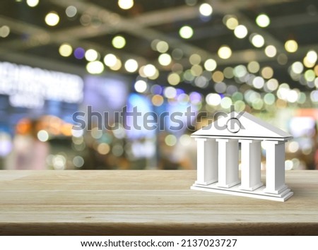 Bank 3d icon on wooden table over blur light and shadow of shopping mall, Business banking online concept