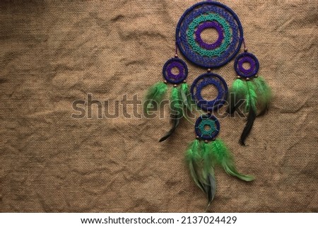 Dream catcher with green and black feathers, on burlap