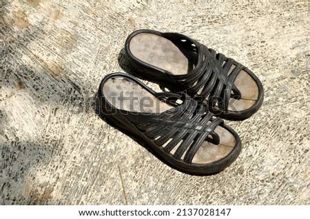 Worn out unbranded sandals on the cement floor