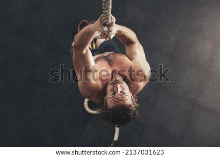 Beast mode comes naturally to me. Shot of a muscular young man climbing a rope in a gym. Royalty-Free Stock Photo #2137031623