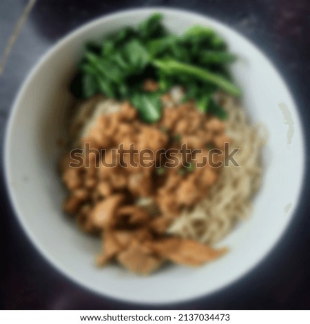 Blurry chicken noodles with mushrooms and green cabbage background
