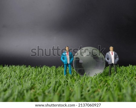 Selective focus.Crystal earth globe with miniature people on a grass background with copy space. Royalty-Free Stock Photo #2137060927