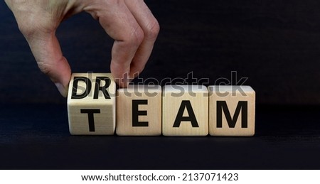 Dream team dreamteam symbol. Businessman turns wooden cubes and changes the word Dream to Team. Beautiful grey table grey background. Business and dream team dreamteam concept, copy space.