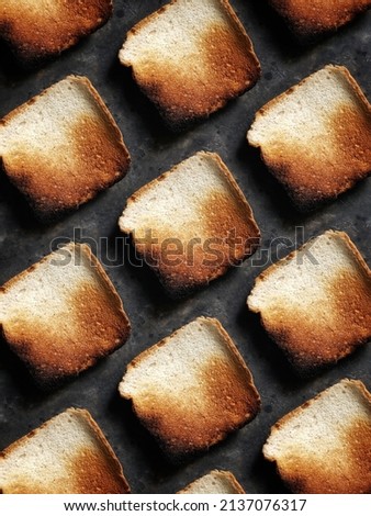 Pattern of burnt bread toasts on a black concrete background