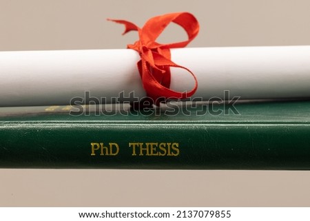 a PhD thesis of green cover with a diploma or certificate Royalty-Free Stock Photo #2137079855