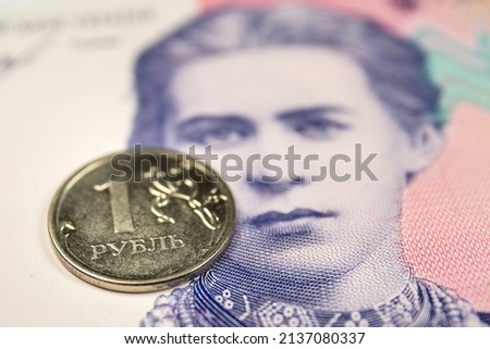 Poland — March 09 2022: In this photo illustration the obverse of the Russian 1-ruble coin and Ukrainian 200-hryvnias banknote with the image of Lesya Ukrainka are seen displayed