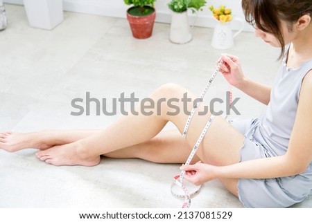 Asian woman measuring her thighs with the tape measure Royalty-Free Stock Photo #2137081529