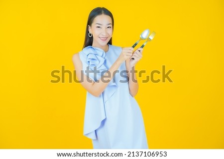 Portrait beautiful young asian woman smile with spoon and fork on color background