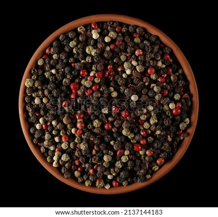 Colorful mixed pepper grains in clay pot isolated on black