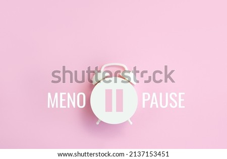Word Menopause, pause sign on a white alarm clock on pink background. Minimal concept hormone replacement therapy. Сopy space Royalty-Free Stock Photo #2137153451