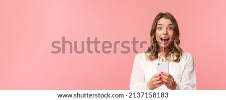 Close-up portrait of excited and amazed young blond girl attend performance of favorite singer, record video, stream online on mobile phone, taking photo with smartphone, look thrilled