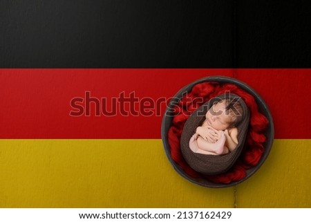 Newborn portrait on background in color of national flag. Patriotic photography concept. Germany