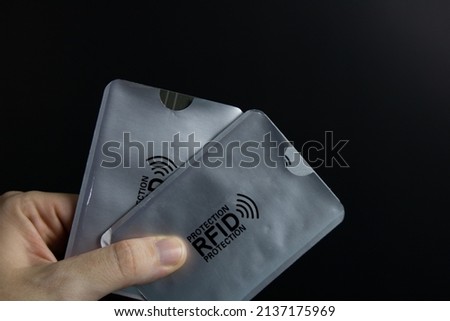 RFID card protection. Woman holding in the finger two cases of a silver RFID card protection.