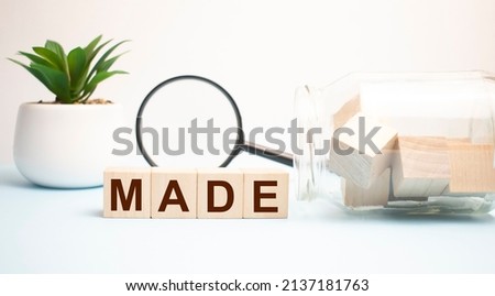 Text MADE on wooden cubes on blue background.