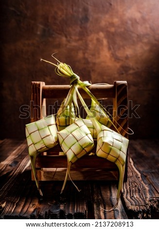 Close up view of Ketupat, an Indonesian traditional cuisine very popular during Hari Raya Idul Fitri served on a wooden table. This is made of the white rice, usually served with opor ayam on Ied day. Royalty-Free Stock Photo #2137208913