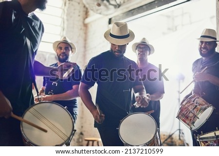 Play it to the beat. Shot of a group of musical performers playing drums together. Royalty-Free Stock Photo #2137210599