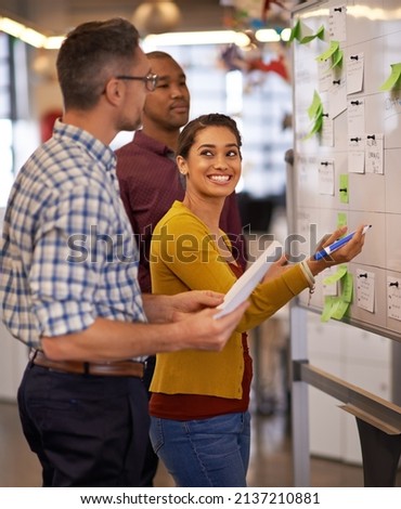 Being creative comes easy to them. Shot of a group of coworkers brainstorming at a whiteboard. Royalty-Free Stock Photo #2137210881