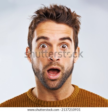 What just happened. Portrait of a shocked young man against a gray background.