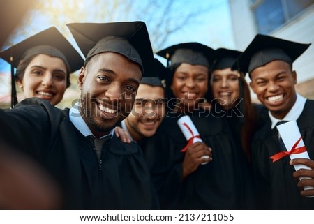 We studied together now were graduating together. Portrait of a group of students taking selfies on graduation day.