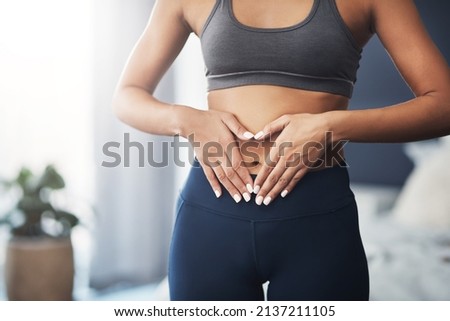 You gotta show love to your body. Cropped shot of an unrecognizable young woman making a heart shape on her stomach in her bedroom. Royalty-Free Stock Photo #2137211105