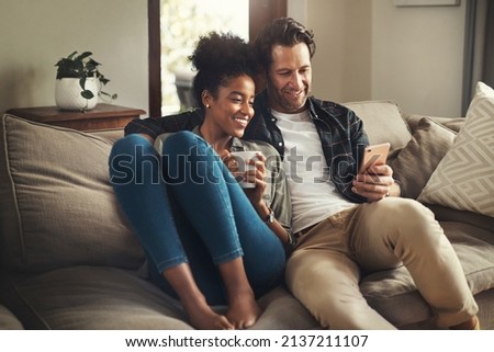 Lock the door, leave the world outside. Shot of a happy young couple using a digital tablet while relaxing on a couch in their living room at home. Royalty-Free Stock Photo #2137211107