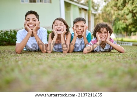 Siblings are best friends you cant live out. Portrait of a group of happy siblings lying together on the grass in their backyard. Royalty-Free Stock Photo #2137211655