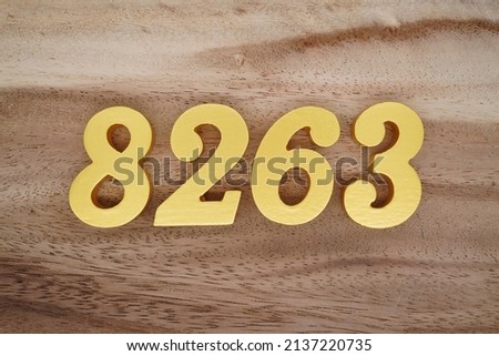 Wooden  numerals 8263 painted in gold on a dark brown and white patterned plank background.