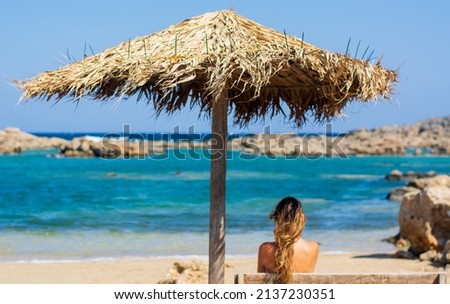 the girl under the umbrella looks at the sea Royalty-Free Stock Photo #2137230351