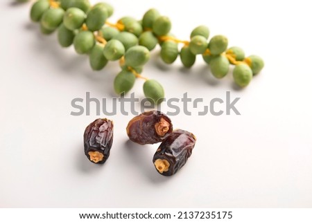 Few ripen dates along with bunch of young, green dates. Sweet, ripen and green dates on white background. Royalty-Free Stock Photo #2137235175