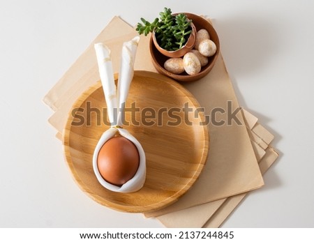 Top view flat lay egg with bunny ears on wooden plate serving for easter celebration.