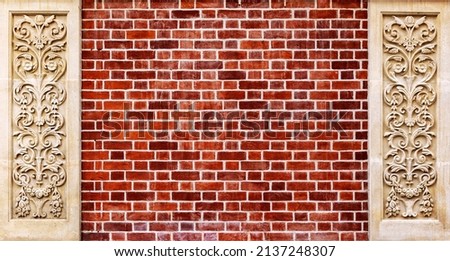 Two Art nouveau style carved panels on a red brick wall. Ornate decorative panel with leaves and flowers. Traditional design in limestone with brick background and space for text. Royalty-Free Stock Photo #2137248307