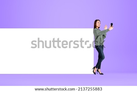 Young woman with device, making video call waving hand on purple background. Concept of online communication and mobile app. Mock up copy space canvas.